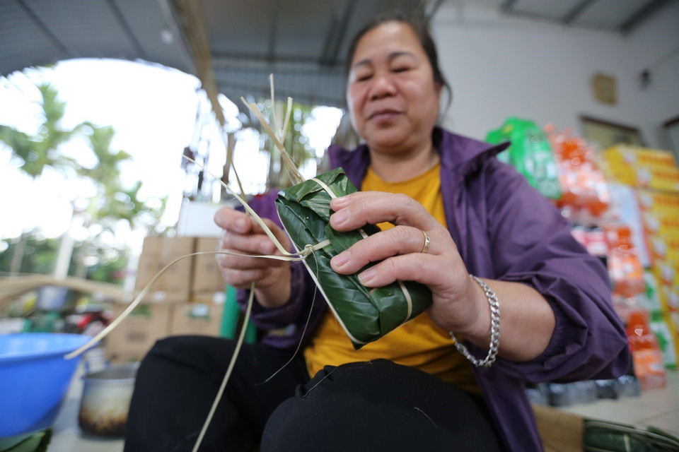 Gói bánh ống đòi hỏi sự khéo léo, cẩn thận để đảm bảo bánh bảo quản được lâu, dền và đẹp mắt. Nếu không khéo bánh rất dễ một đầu to, một đầu nhỏ và lỏng lẻo. (Ảnh: Trọng Đạt/TTXVN)