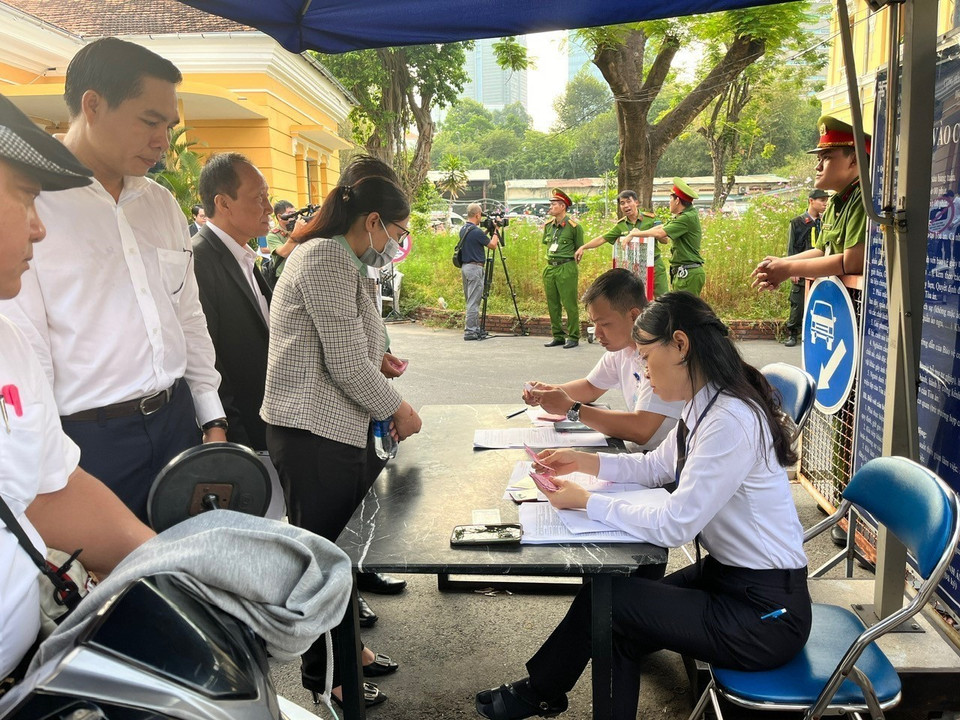 Luật sư, phóng viên báo chí, người được triệu tập được kiểm tra an ninh trước khi vào khu vực phiên tòa xét xử. (Ảnh: Thanh Vũ/TTXVN)