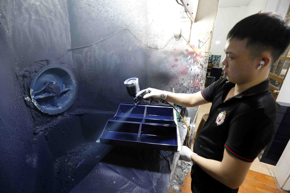 Một công đoạn phun sơn trên sản phẩm khay đựng đồ tại Công ty Thái Sơn, làng nghề Hạ Thái. (Ảnh: Trần Việt/TTXVN)