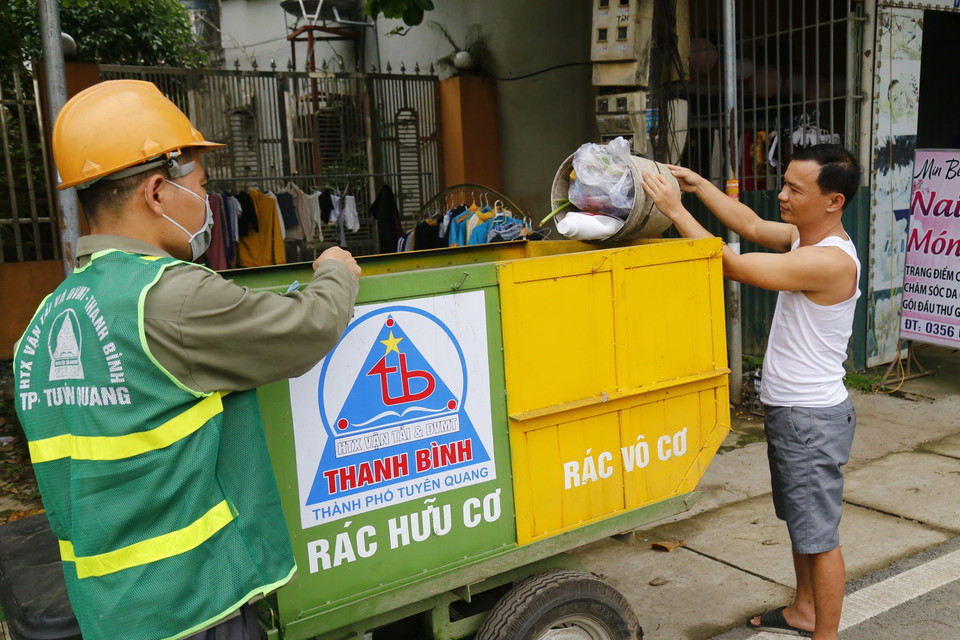  Công nhân Hợp tác xã Vận tải và Dịch vụ môi trường Thanh Bình (xã Lưỡng Vượng, thành Phố Tuyên Quang, tỉnh Tuyên Quang) hướng dẫn người dân phân loại rác trực tiếp trong quá trình thu gom. Việc thu gom, phân loại và tái chế rác thải nhựa của HTX đã giải quyết lượng rác thải nhựa đang ngày một tăng cao ngoài môi trường. Đồng thời tạo thêm công ăn việc làm và thu nhập cho khoảng 20 công nhân chủ yếu là người yếu thế, mất sức lao động, với mức thu nhập bình quân từ 4,5 đến 6 triệu đồng/người/tháng. (Ảnh: Nam Sương/TTXVN)