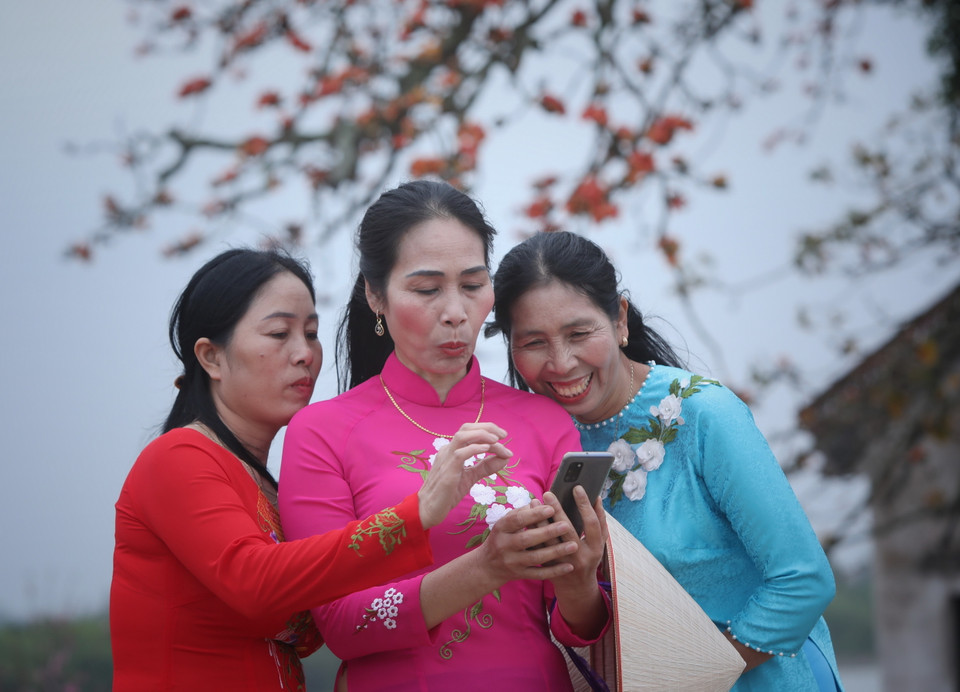 Du khách thích thú với những bức ảnh vừa chụp tại cây gạo miếu Bà Cô. (Ảnh: Danh Lam/TTXVN)