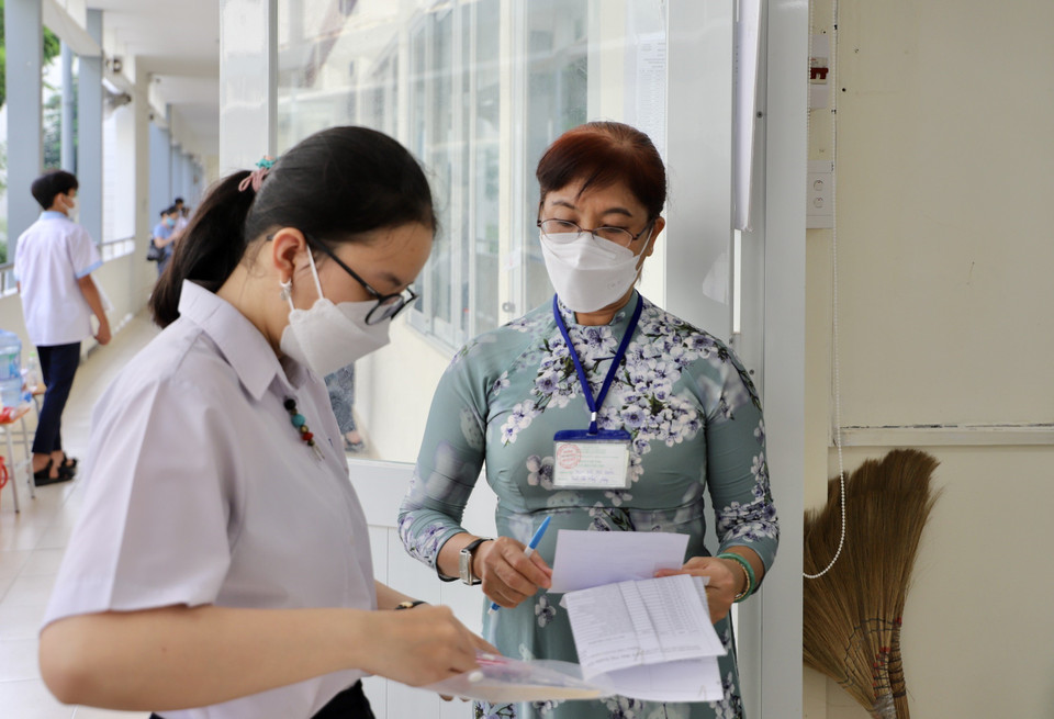 Các thí sinh tại điểm thi trường Trung học phổ thông Bùi Thị Xuân (Quận 1) được giám thị kiểm tra thông tin cá nhân trước khi vào phòng thi. (Ảnh: Hồng Giang/TTXVN)