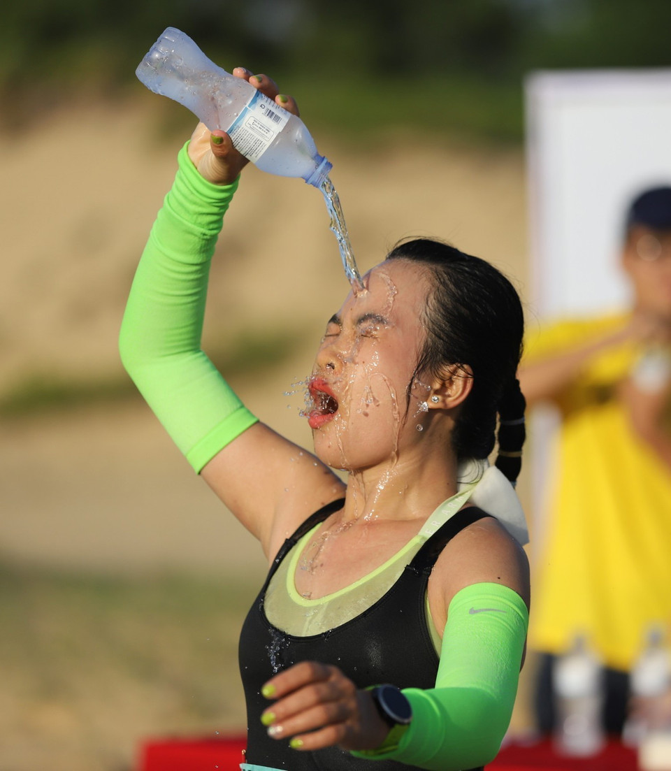 Vận động viên nữ chạy cự ly 42km tiếp nước để hạ nhiệt. (Ảnh: Nguyên Linh/TTXVN)