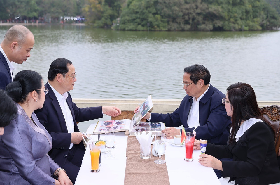 Thủ tướng Phạm Minh Chính và Phu nhân cùng Thủ tướng Sonexay Siphandone và Phu nhân xem lại hình ảnh chuyến thăm. (Ảnh: Dương Giang/TTXVN)