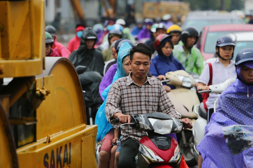 Người dân len lỏi giữa hàng loạt phương tiện xe máy công trình. (Ảnh: Thành Đạt/TTXVN)