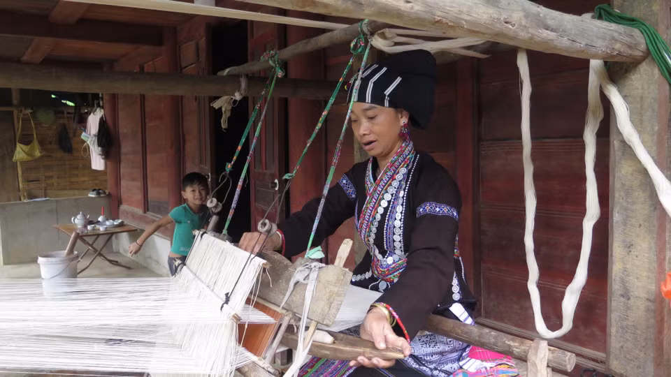 Người phụ nữ Lự tận dung thời gian rảnh rỗi để dệt những bộ quần áo cho gia đình. (Ảnh: Việt Hoàng/TTXVN)