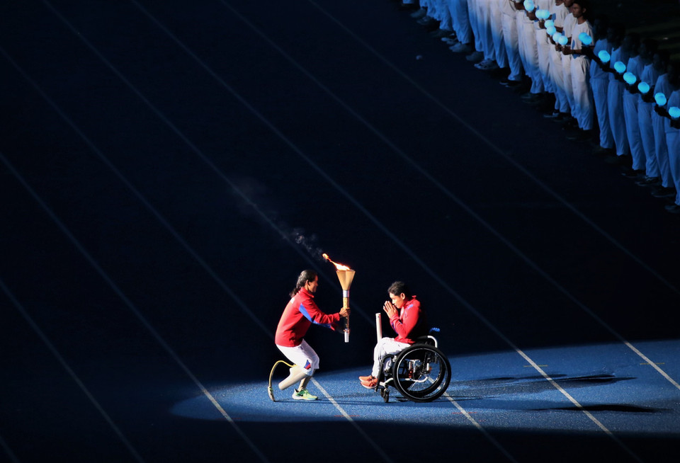 Vận động viên Vat Chanthan di chuyển ra khu vực đường piste để trao đuốc cho vận động viên tiếp theo. (Ảnh: Huỳnh Thảo/TTXVN)