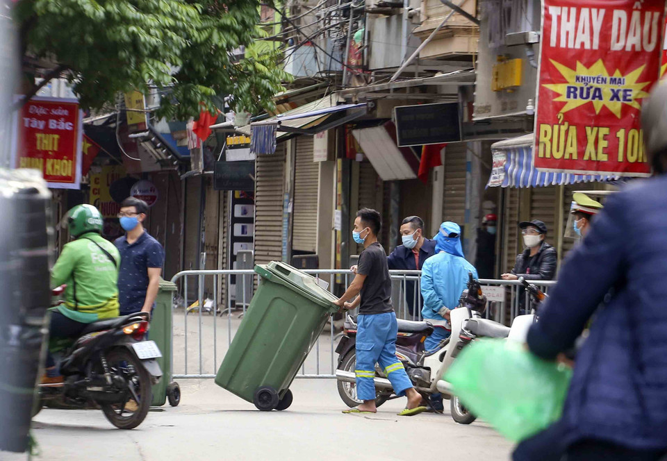 Lực lượng công nhân vệ sinh thu dọn rác thải tại khu vực phong tỏa. (Ảnh: Tuấn Đức/TTXVN)