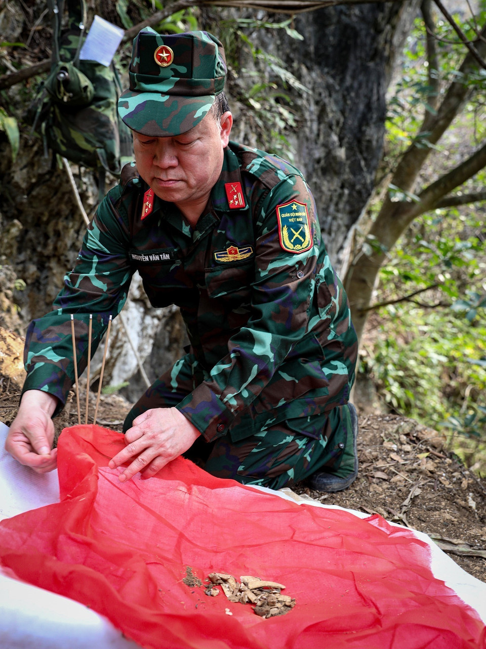 Thượng tá Nguyễn Văn Tân - Chính trị viên đội Tìm kiếm quy tập hài cốt liệt sỹ thắp nén hương tại nơi tìm được hài cốt các chiến sĩ đã hi sinh (ảnh chụp tại xã Thanh Thủy, huyện Vị Xuyên). (Ảnh: Hoàng Hiếu/TTXVN)