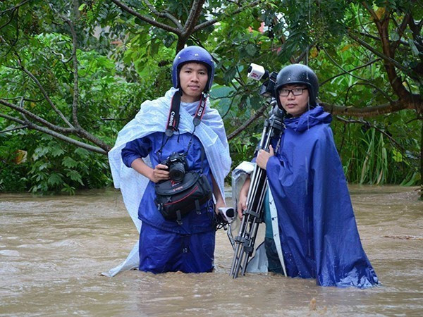 Các phóng viên Trịnh Xuân Tư (trái) và Võ Văn Dũng (TTXVN) tác nghiệp trong trận mưa lũ gây ngập lụt cục bộ tại Thành phố Điện Biên Phủ năm 2018. (Nguồn: TTXVN)