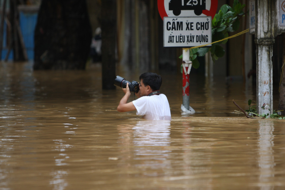 Phóng viên ảnh Xuân Trường (TTXVN) dầm mình trong nước để tác nghiệp về tình hình mưa lũ (9/2009). (Nguồn: TTXVN)