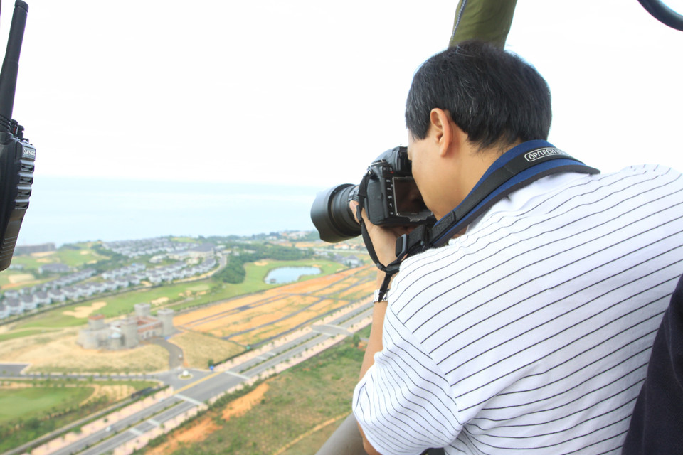 Phóng viên Quang Hải (TTXVN) tác nghiệp từ trên khinh khí cầu tại Lễ hội khinh khí cầu quốc tế Việt Nam lần thứ I năm 2012 ở Bình Thuận. (Ảnh: Nhật Anh/TTXVN)