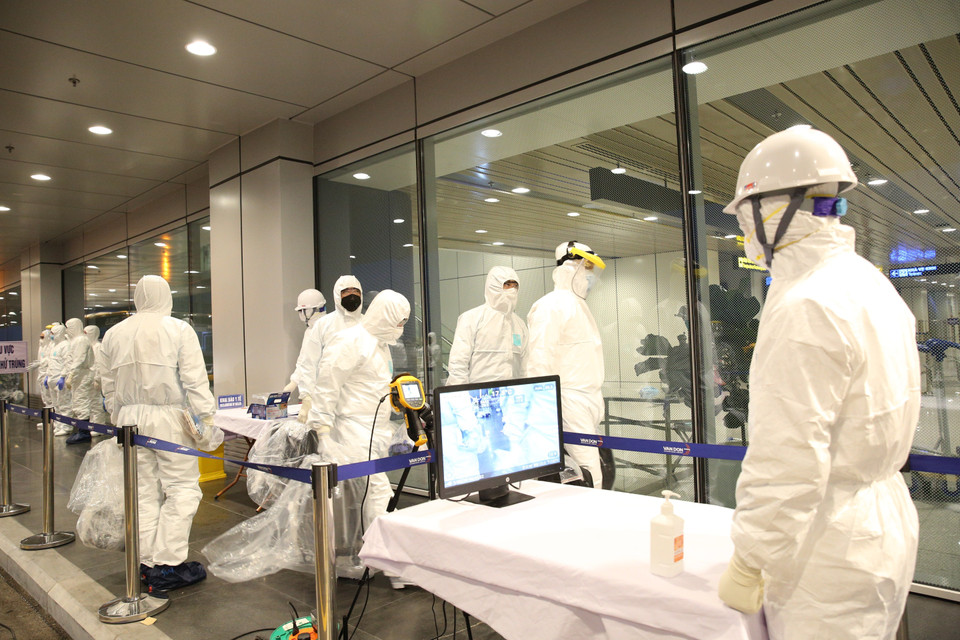 Kiểm tra thân nhiệt, khử trùng người và phương tiện trước khi làm thủ tục nhập cảnh. (Ảnh: Dương Giang/TTXVN)