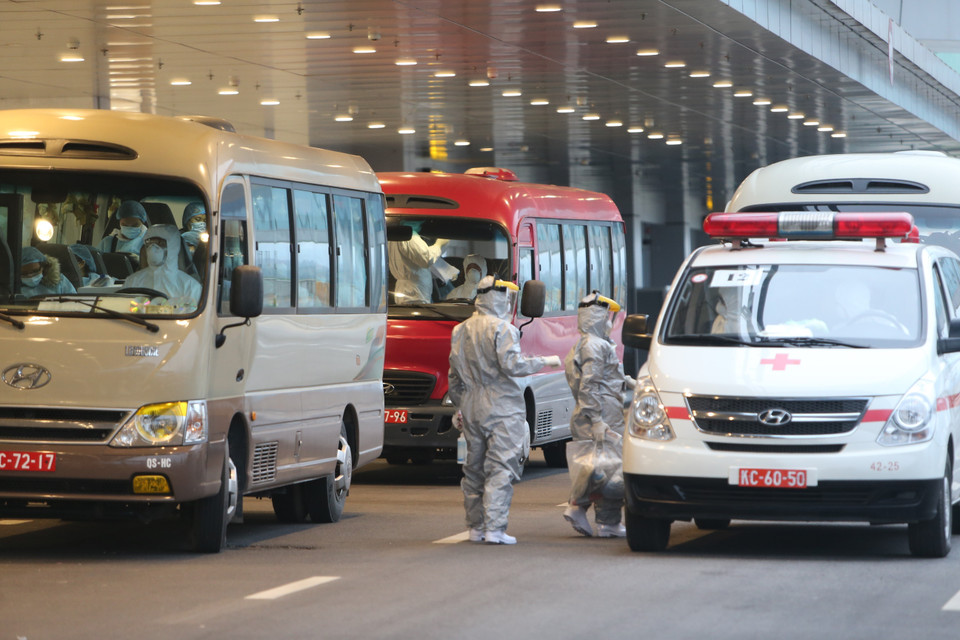 Các công dân Việt Nam được đưa lên xe ôtô đã khử trùng rời sân bay Vân Đồn đến khu vực cách ly để theo dõi và điều trị. (Ảnh: Dương Giang/TTXVN)