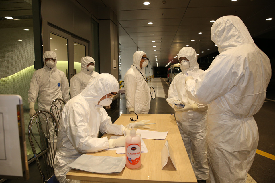 Nhân viên Cảng hàng không sân bay Vân Đồn làm thủ tục nhập cảnh cho công dân Việt Nam trở về từ Vũ Hán (Trung Quốc). (Ảnh: Dương Giang/TTXVN)