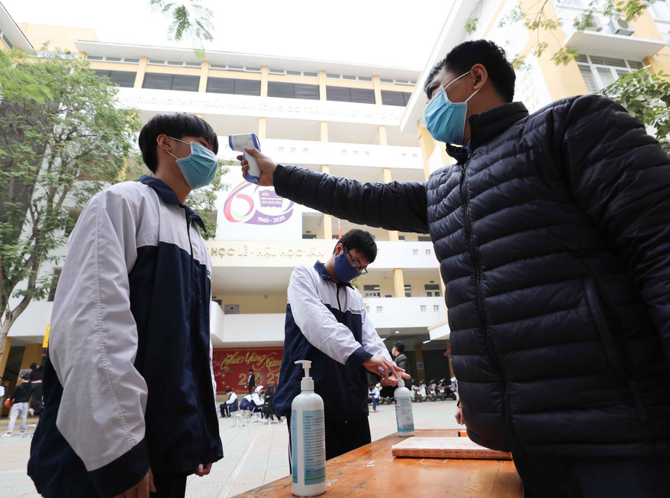 Trường THPT Trần Nhân Tông, quận Hai Bà Trưng (Hà Nội) thực hiện đo thân nhiệt, sát khuẩn tay cho cán bộ, giáo viên và học sinh mỗi khi ra, vào trường (ảnh chụp sáng 29/1). (Ảnh: Thanh Tùng/TTXVN)