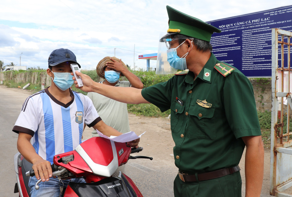 Lực lượng Bộ đội biên phòng đo thân nhiệt cho lao động vào cảng. (Ảnh: Phạm Cường/TTXVN)