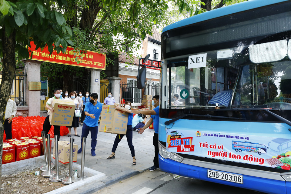 Cán bộ, nhân viên Liên đoàn Lao động thành phố Hà Nội vận chuyển hàng lên xe buýt siêu thị 0 đồng. (Ảnh: Minh Đức/TTXVN)