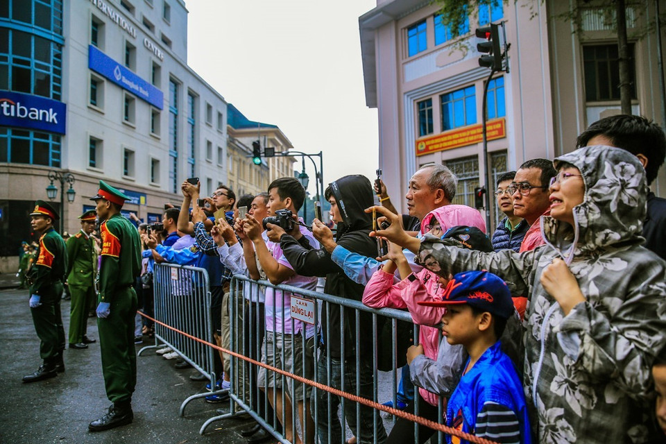 Người dân đứng bên đường nơi đoàn xe chở Tổng thống Hoa Kỳ Donald Trump sẽ di chuyển qua. (Ảnh: Trọng Đạt/TTXVN)