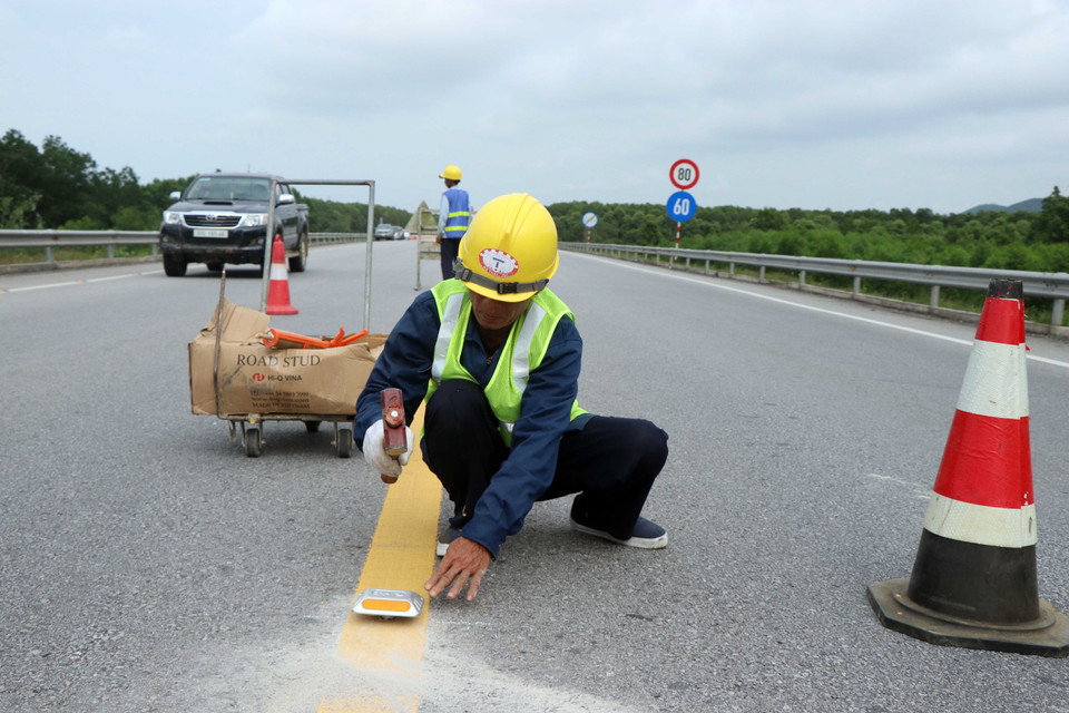 Thi công bổ sung lắp đặt các đinh phản quang giữa tim đường có hai làn xe. (Ảnh: Đỗ Trưởng/TTXVN)