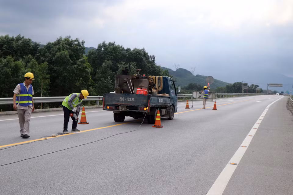 Thi công bổ sung lắp đặt các đinh phản quang giữa tim đường có hai làn xe. (Ảnh: Đỗ Trưởng/TTXVN)