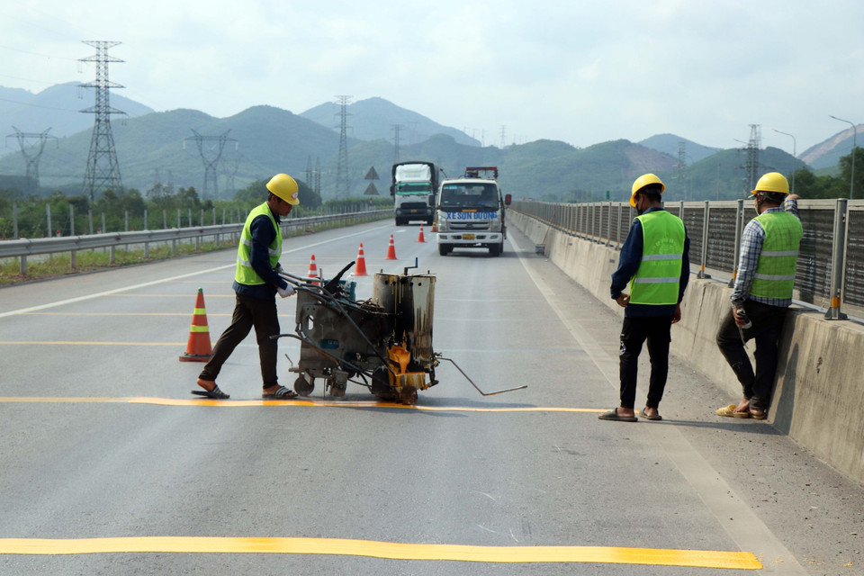 Thi công bổ sung sơn vạch gờ giảm tốc tại các nút giao chuyển từ bốn làn xe xuống hai làn xe. (Ảnh: Đỗ Trưởng/TTXVN)