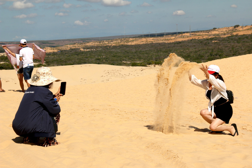 Du khách thích thú với điểm đến đồi cát Bàu Trắng với khung cảnh hoang sơ và cực kỳ ấn tượng. (Ảnh: Nguyễn Thanh/TTXVN)