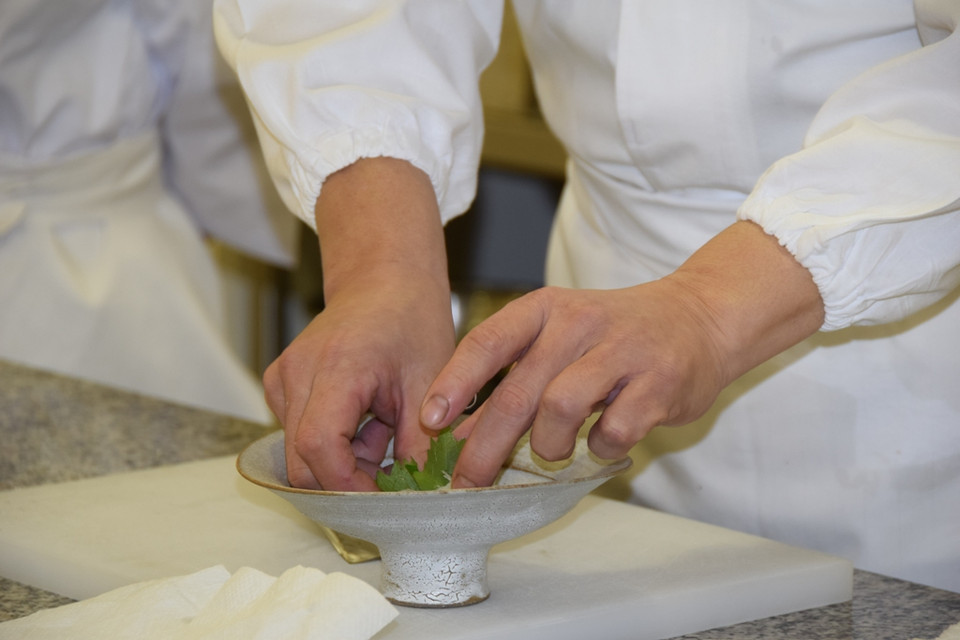 Bếp trưởng xếp lá tía tô vào đĩa sâu lòng để bày sashimi