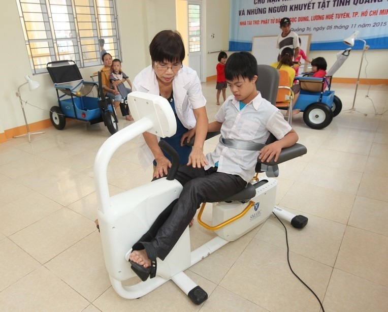 Nhân viên Trung tâm Nuôi dưỡng, phục hồi chức năng và dạy nghề cho nạn nhân chất độc da cam tại thành phố Đông Hà, tỉnh Quảng Trị giúp các trẻ là nạn nhân chất độc da cam/dioxin tập phục hồi chức năng (2015). (Ảnh: Anh Tuấn/TTXVN)