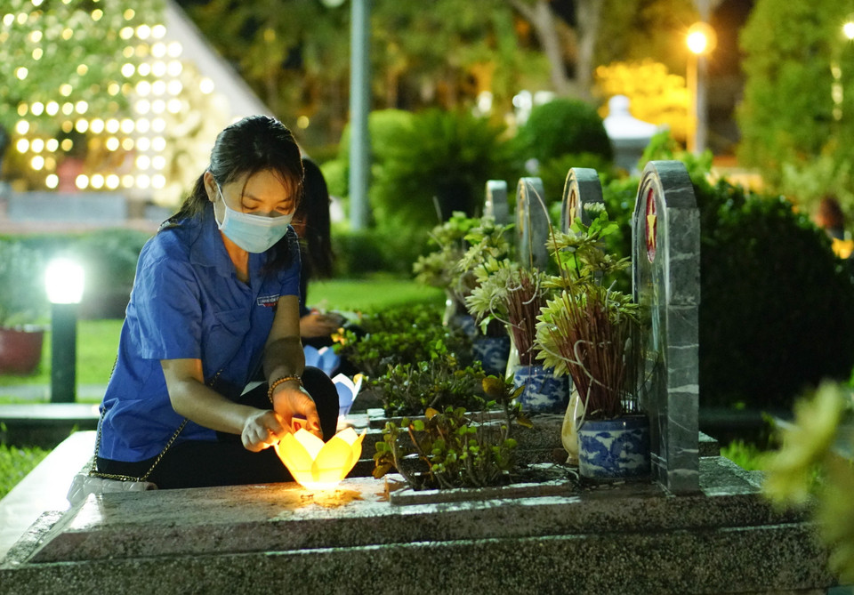 Đoàn viên thanh niên thắp nến trên các phần mộ liệt sỹ. (Ảnh: Xuân Tư/TTXVN)