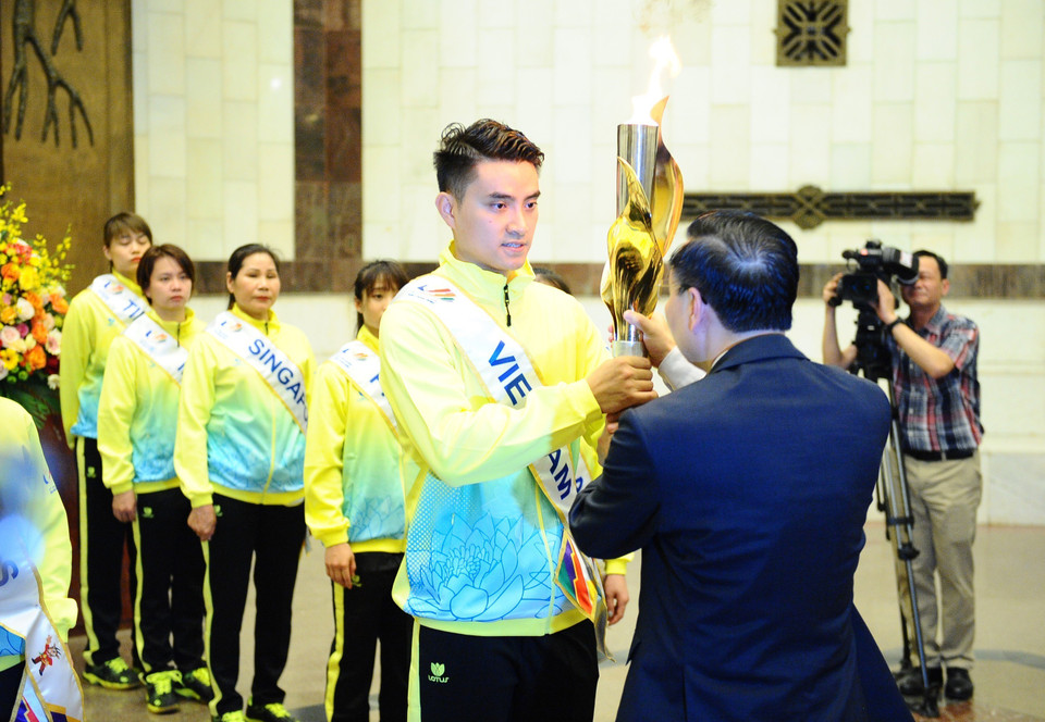 Chủ tịch thành phố Hà Nội Chu Ngọc Anh trao ngọn lửa cho vận động viên tiêu biểu. (Ảnh: Minh Đức/TTXVN)