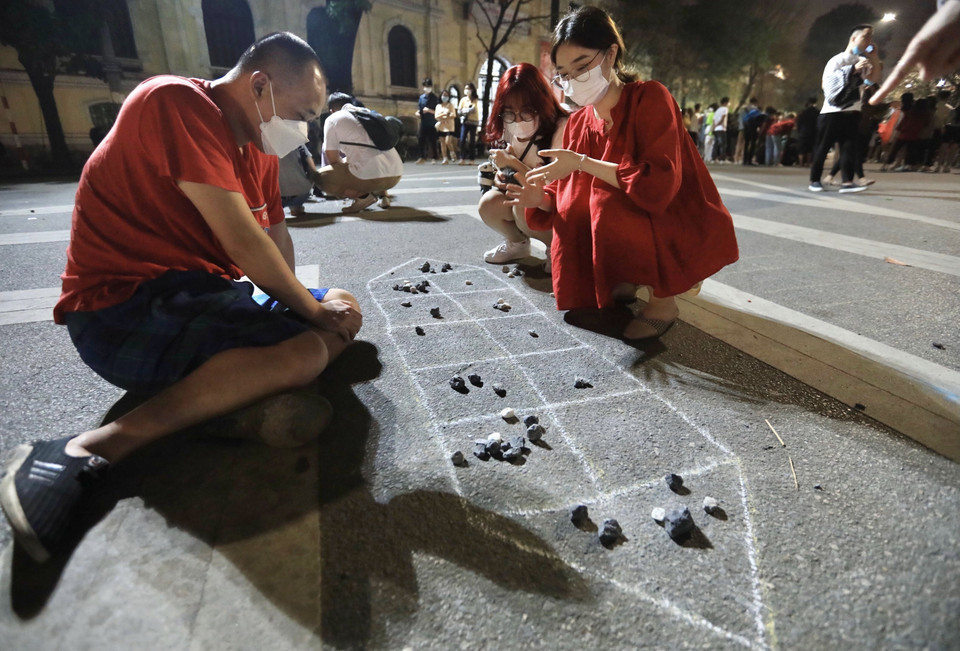 Nhiều bạn trẻ chơi ô ăn quan trên phố đi bộ Đinh Tiên Hoàng.(Ảnh: Hoàng Hiếu/TTXVN)