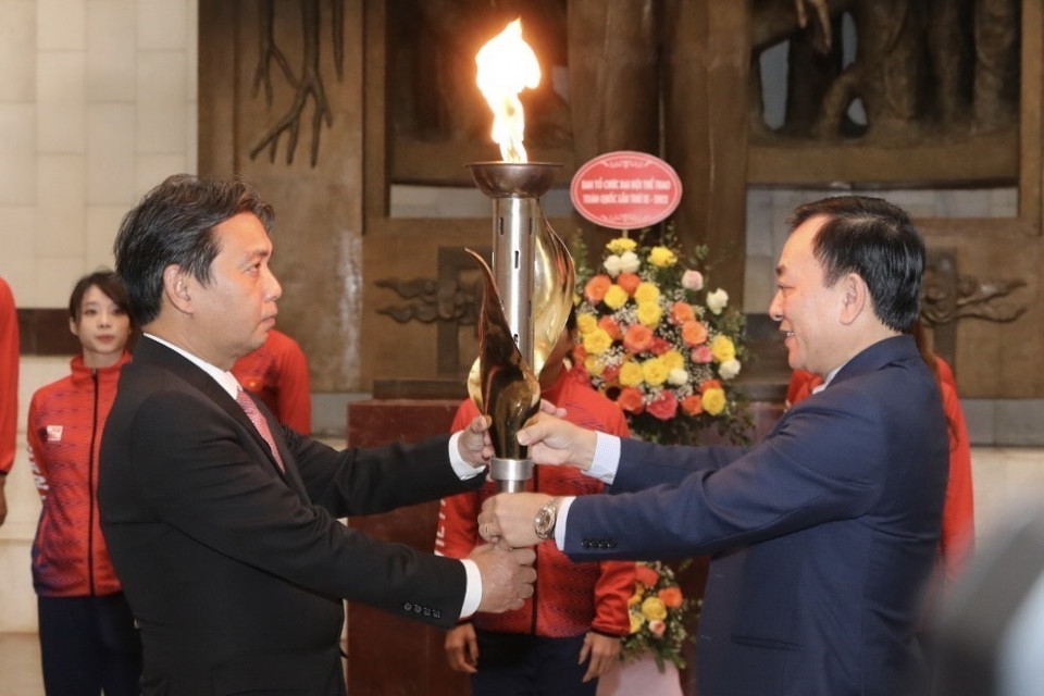 Tiến sỹ Vũ Mạnh Hà, Giám đốc Bảo tàng Hồ Chí Minh trao đuốc cho Thứ trưởng Bộ Văn hóa Thể thao và Du lịch Hoàng Đạo Cương. (Ảnh: Minh Quyết/TTXVN)