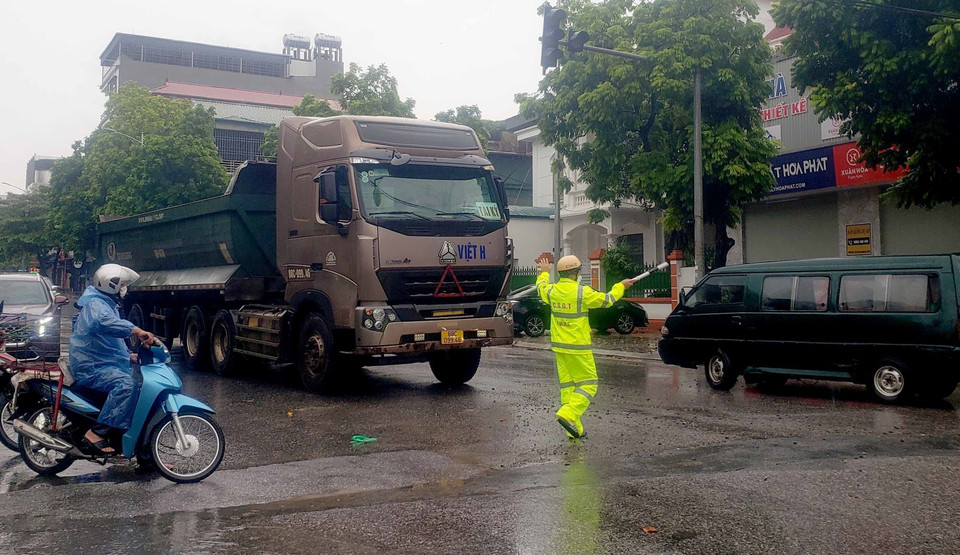 Cảnh sát giao thông phân luồng cho các phương tiện tham gia giao thông tránh đi vào các vùng bị ngập nước tại thành phố Vĩnh Yên. (Ảnh: Hoàng Hùng/TTXVN)