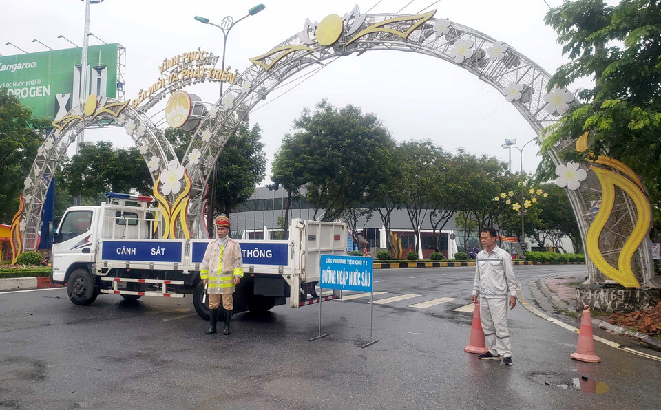 Cảnh sát giao thông phân luồng cho các phương tiện tham gia giao thông tránh đi vào các vùng bị ngập nước tại thành phố Vĩnh Yên. (Ảnh: Hoàng Hùng/TTXVN)