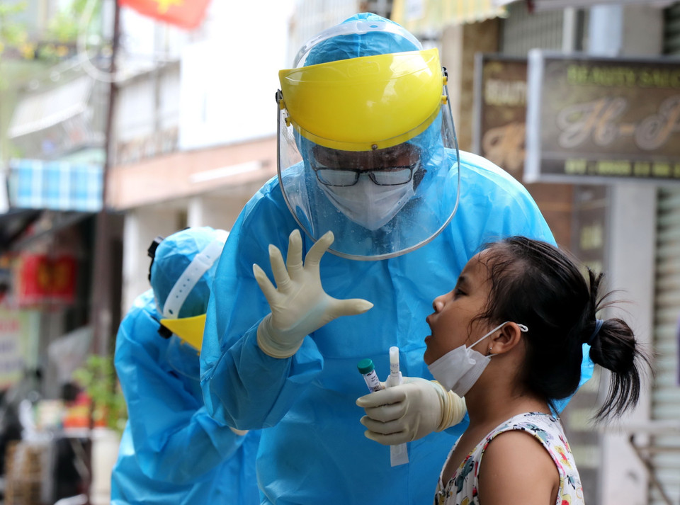 Nhân viên y tế động viên bé gái trước khi tiến hành lấy mẫu sinh phẩm. (Ảnh: Quốc Dũng/TTXVN)