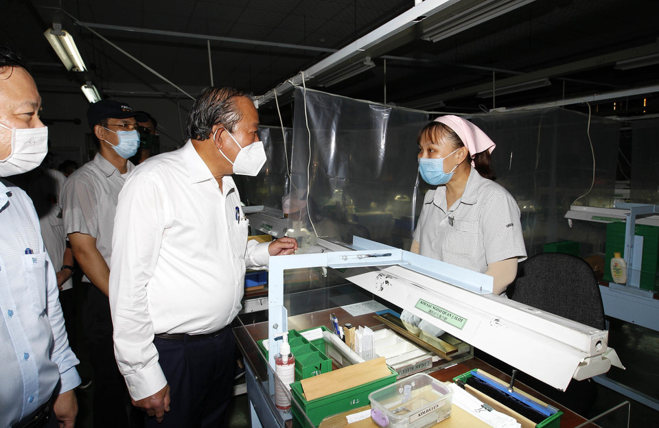 Phó Thủ tướng thường trực Chính phủ Trương Hòa Bình thăm hỏi công nhân tham gia phòng, chống dịch bệnh tại Công ty trách nhiệm hữu hạn Kim may Organ, nơi có khoảng 1.250 lao động, chuyên sản xuất các loại kim may. (Ảnh: Thanh Vũ/TTXVN)