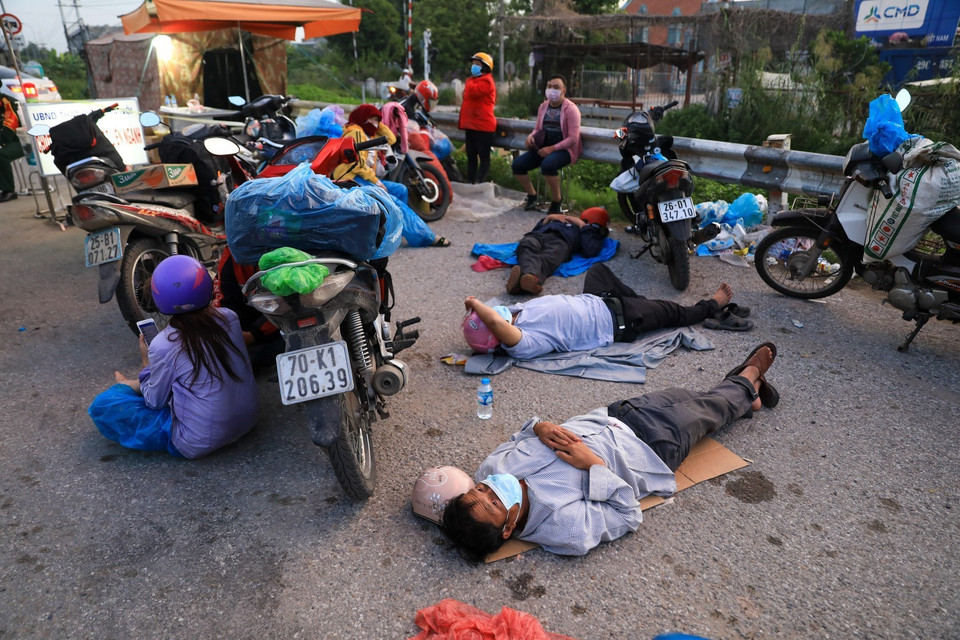 Sau nhiều ngày di chuyển, người dân nghỉ tạm trên đường tại trạm nghỉ QL1A. (Ảnh: Thành Đạt/TTXVN)