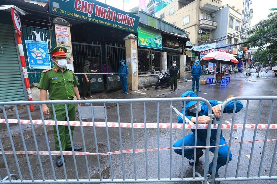 Lực lượng chức năng lập hàng rào ngăn khu vực phong tỏa chợ Nhân Chính. (Ảnh: Tuấn Anh/TTXVN)