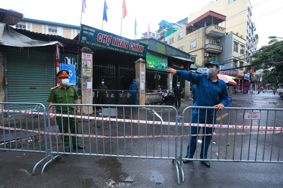 Lực lượng chức năng hướng dẫn người dân di chuyển khỏi khu vực giáp ranh chợ Nhân Chính. (Ảnh: Tuấn Anh/TTXVN)