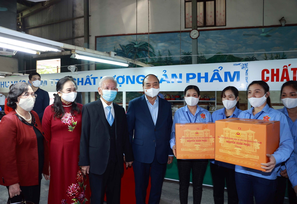 Chủ tịch nước Nguyễn Xuân Phúc tặng quà cho công nhân Công ty TNHH sản xuất dịch vụ thương mại sản phẩm da LADODA (xã Tân Quang, huyện Văn Lâm, tỉnh Hưng Yên), do ông Đinh Quang Bào, 83 tuổi là đại diện pháp luật. (Ảnh: Thống Nhất/TTXVN)
