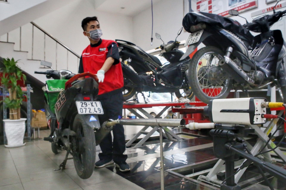 Các nhân viên kiểm tra khí thải xe máy. (Ảnh: Tuấn Đức/TTXVN)