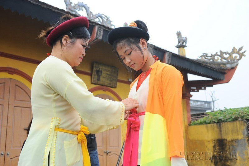 Thế hệ nghệ sỹ sau nối tiếp thế hệ trước, giữ nghề bằng cách truyền nghề trực tiếp, bắt tay chỉ ngón, dạy từng cách diễn, cách hát hay trang phục biểu diễn. Trong ảnh: Nghệ nhân Vũ Thị Lan (bên trái), làng Khuốc, xã Phong Châu, huyện Ðông Hưng (Thái Bình) được coi là nơi khởi nguồn của chèo, hướng dẫn cháu Hoàng Mai Trang cách mặc trang phục chèo truyền thống. (Ảnh: Minh Đức/TTXVN)