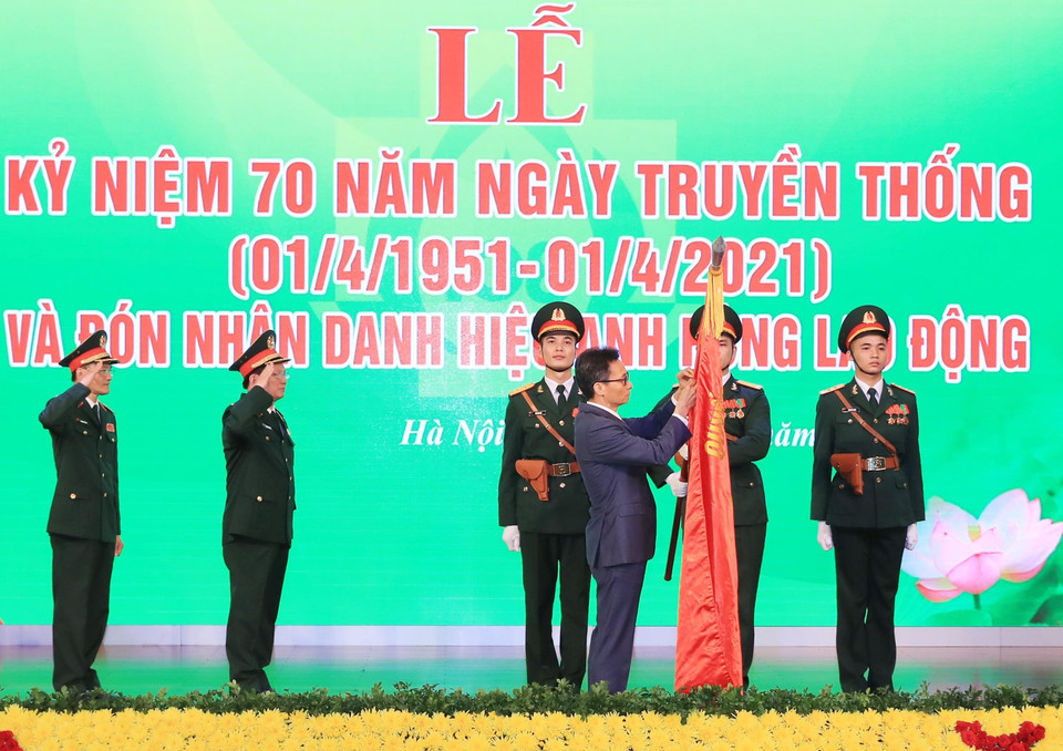 Phó Thủ tướng Vũ Đức Đam gắn Danh hiệu Anh hùng Lao động thời kỳ đổi mới lên lá cờ truyền thống của Bệnh viện Trung ương Quân đội 108. (Ảnh: TTXVN)