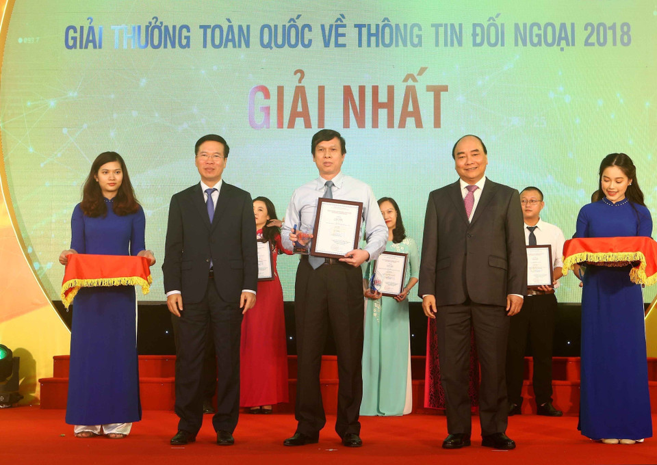 Thủ tướng Nguyễn Xuân Phúc và Trưởng ban Tuyên giáo Trung ương, Trưởng ban Chỉ đạo Công tác thông tin đối ngoại Trung ương Võ Văn Thưởng trao giải nhất Giải thưởng toàn quốc thông tin đối ngoại năm 2018 cho tác giả Lê Trí Dũng (TTXVN), ngày 7/6/2019, tại Hà Nội. (Ảnh: Doãn Tấn/TTXVN)