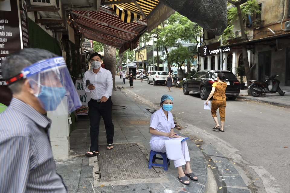 Lực lượng chức năng nhắc nhở người dân khai báo y tế và lấy mẫu xét nghiệm COVID-19 tại phố Nguyễn Khắc Cần. (Ảnh: Minh Quyết/TTXVN)