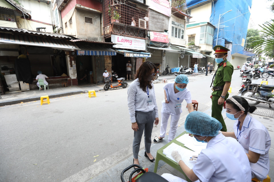 Lực lượng chức năng nhắc nhở người dân khai báo y tế và lấy mẫu xét nghiệm COVID-19 tại phố Nguyễn Khắc Cần. (Ảnh: Minh Quyết/TTXVN)