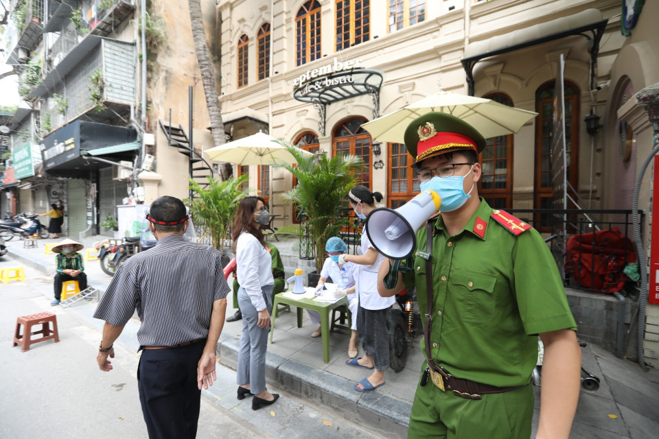 Lực lượng chức năng nhắc nhở người dân khai báo y tế và lấy mẫu xét nghiệm COVID-19 tại phố Nguyễn Khắc Cần. (Ảnh: Minh Quyết/TTXVN)