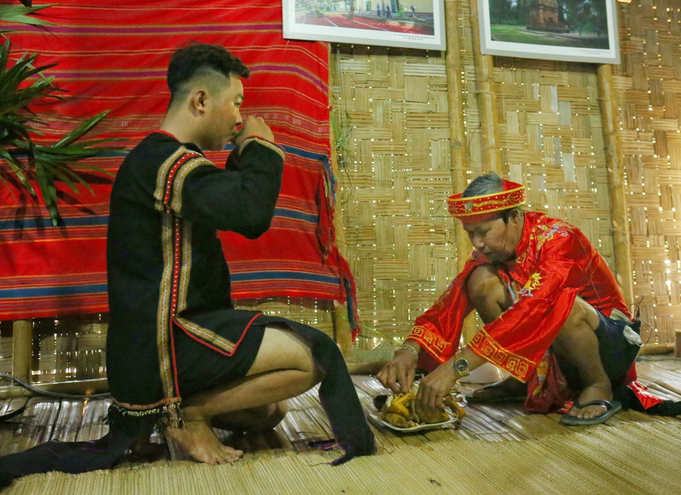 Thầy cúng mời rượu và thịt cho các thành viên trong gia đình. (Ảnh: Lê Thùy Dương/TTXVN phát)