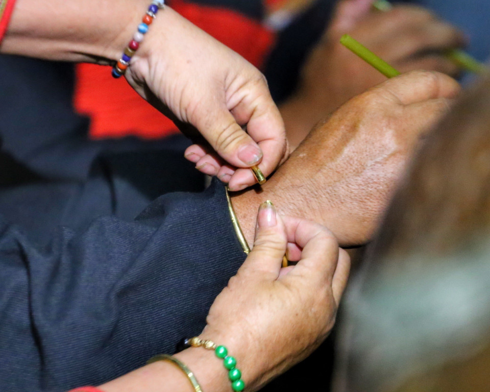 Đeo vòng cầu may mắn cho các thành viên trong gia đình. (Ảnh: Tuấn Đức/TTXVN)